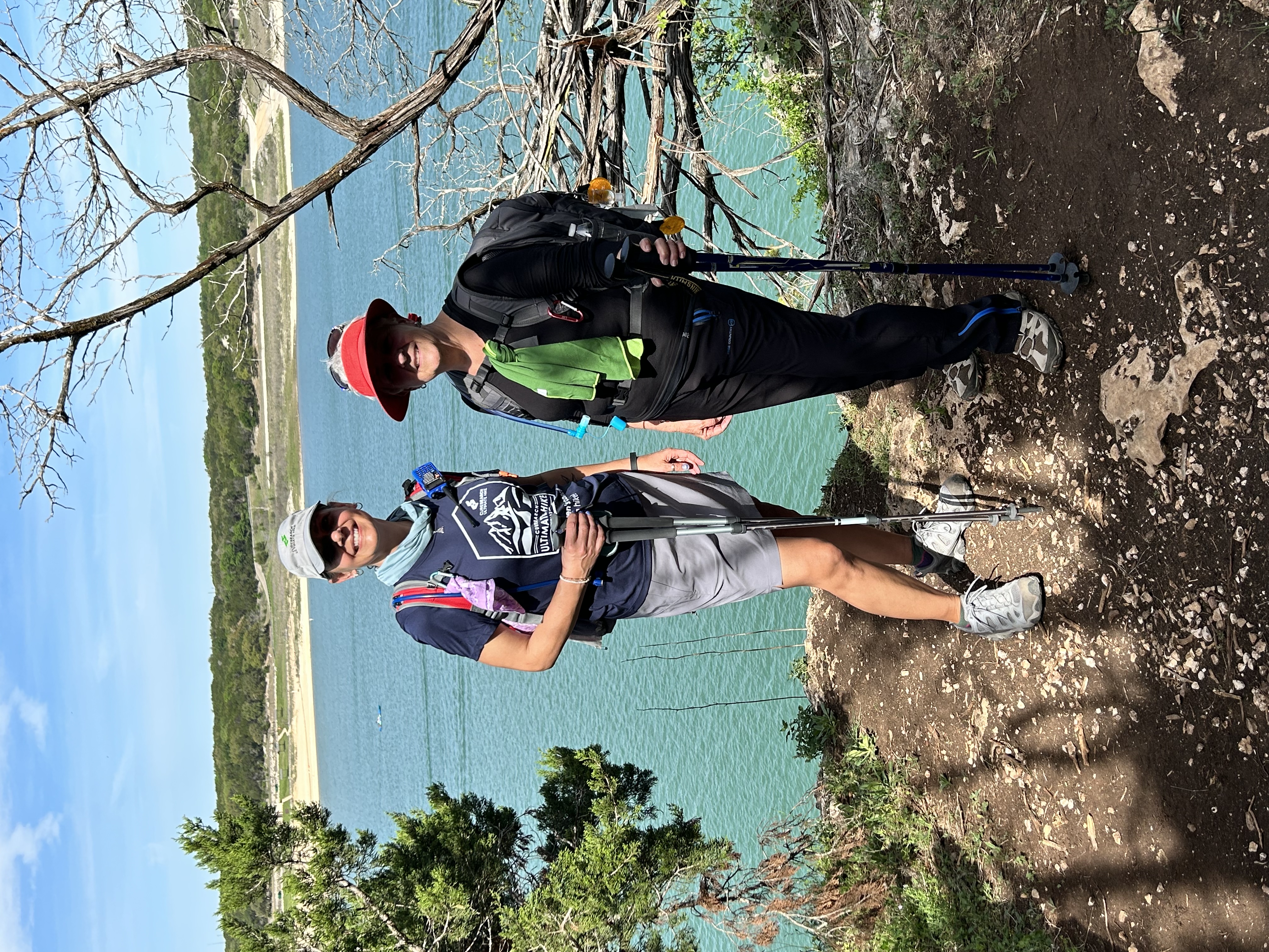 Two Ultimate Hike participants smiling together beside a Central Texas lake
