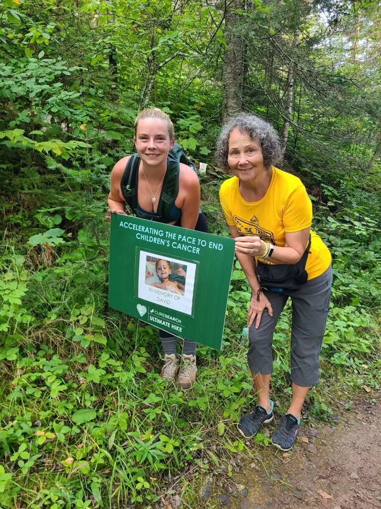 Two Ultimate Hike participants on the trail holding a sign in memory of David