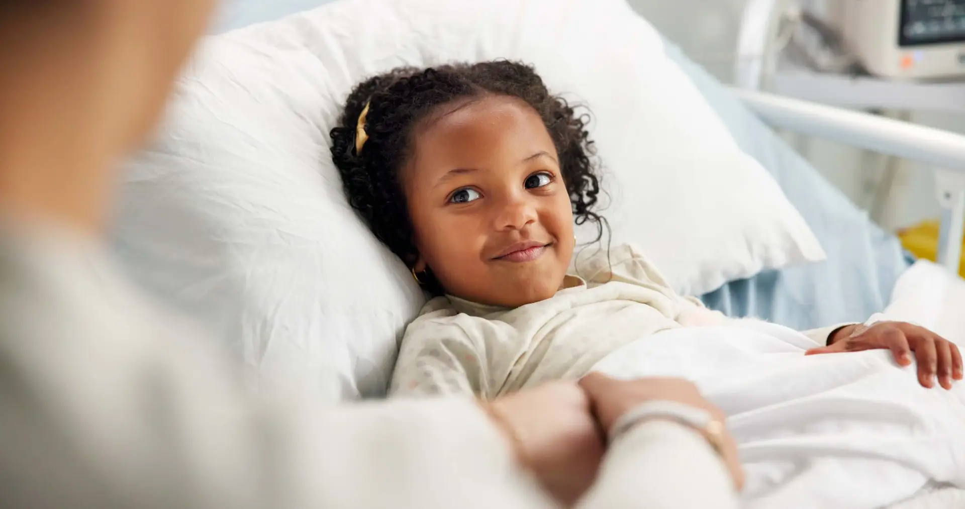 A smiling young patient resting in a hospital bed