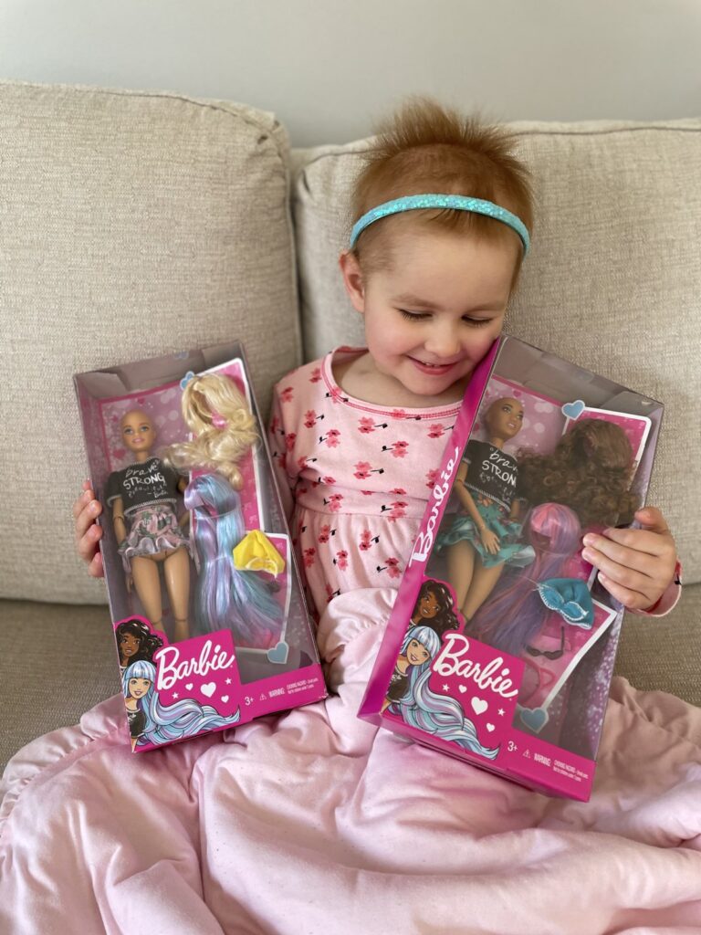 Emilia holds up her Brave Barbie dolls