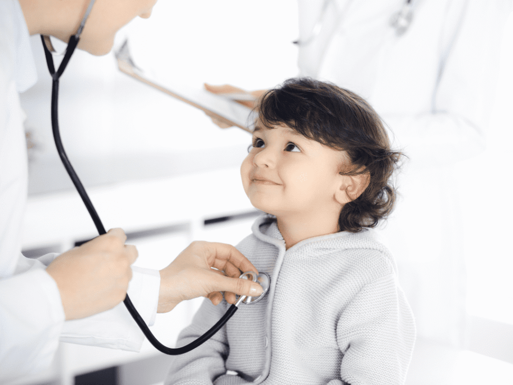 A young child smiles during a checkup with a doctor