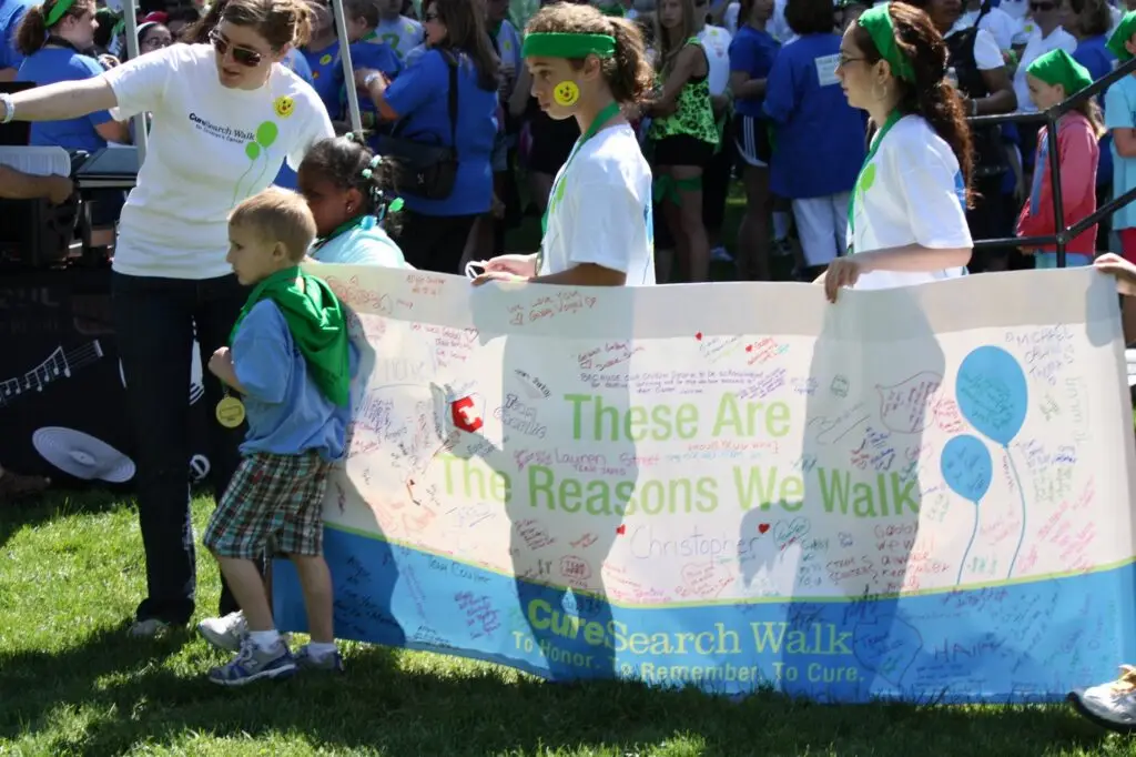 Kids carrying a "These Are the Reasons We Walk" banner at a CureSearch Walk