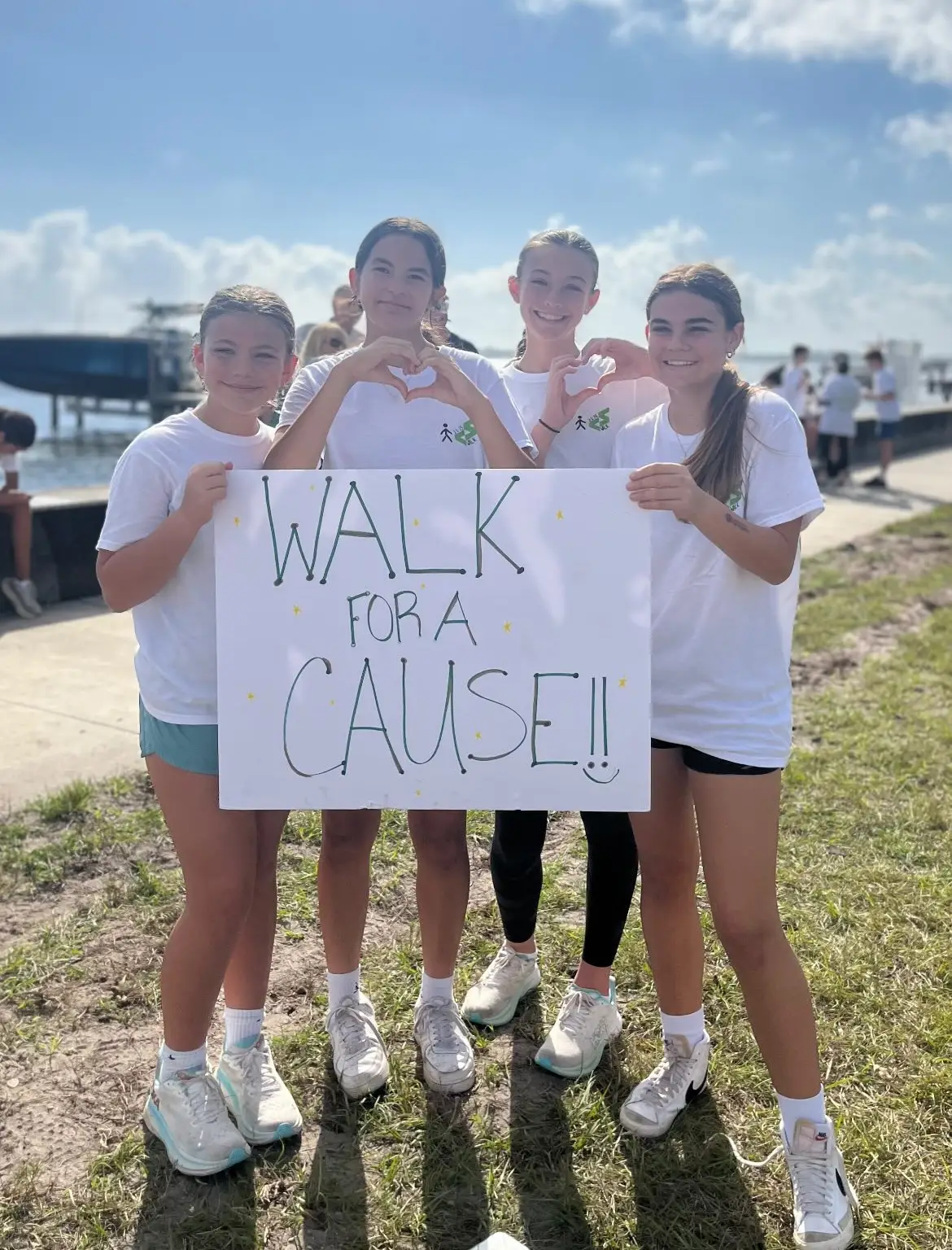 Four young walkers in CureSearch Walk shirts hold a “Walk for a Cause” sign