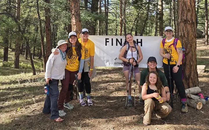 Colorado Trail Ultimate Hike participants at the finish line in a pine forest