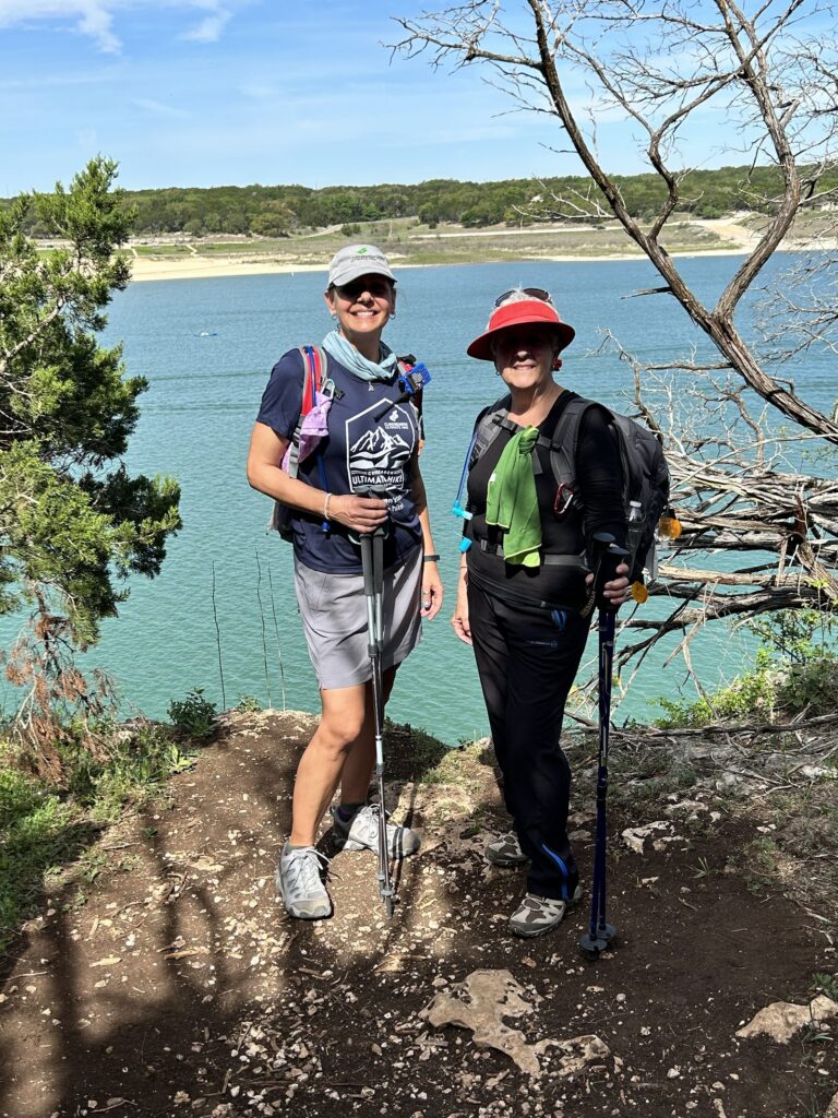 Two Ultimate Hike participants smiling together beside a Central Texas lake