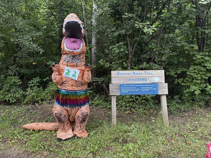 A hiker in a dinosaur costume at a Minnesota trailhead