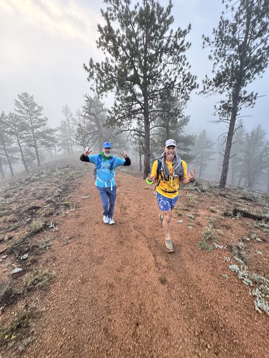 Two hikers waving on a foggy Colorado trail