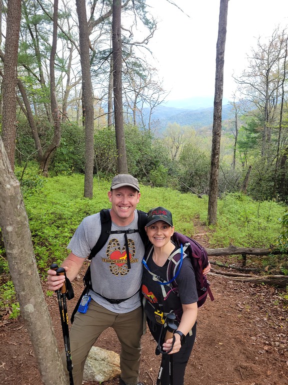 Two hikers on the Foothills Trail with a mountain view behind them